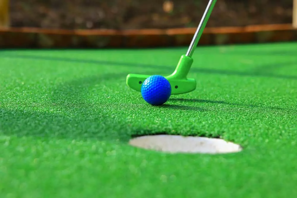 blue golf ball being putted in hole