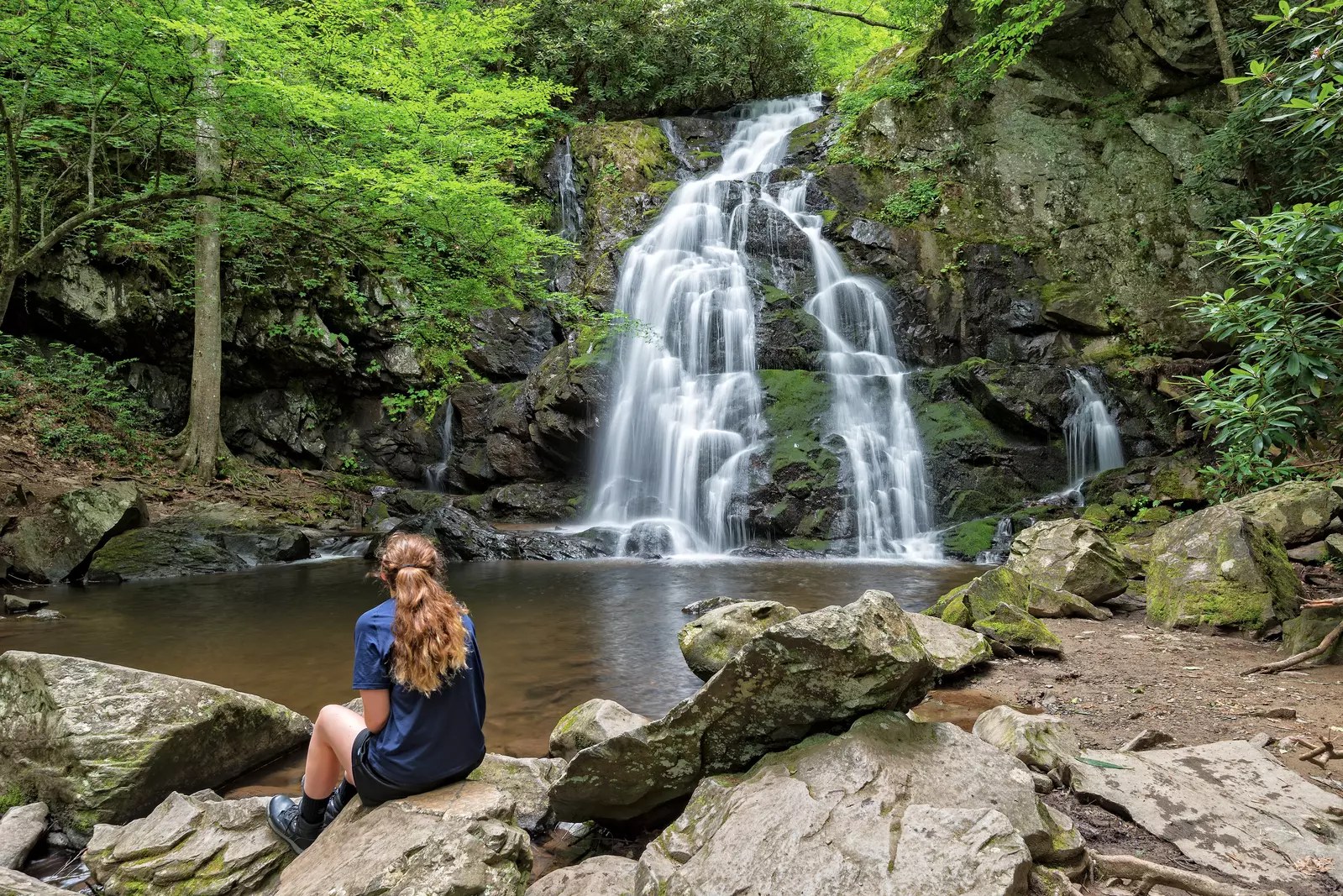 hiker sitting in front of a waterfall
