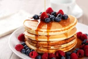 stack of pancakes with berries and syrup