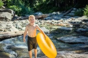 little boy coming out of river with yellow inner tube
